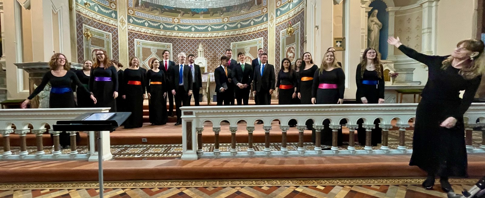 Image shows a choir with a the choir master introduces them.
